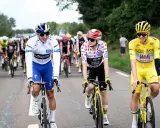 Radfahrer in bunten Trikots, Teil der Tour de France Teams, fahren auf der Straße. Einer trägt das Gelbe Trikot.