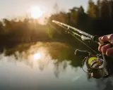 Poranek nad jeziorem, słońce wschodzi, mgła unosi się nad wodą. Dłoń trzyma wędkę, gotową do łowienia. To idealny moment na street fishing.