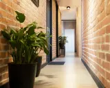 Przedpokój loft inspiracje: ceglane ściany, jasna podłoga, czarne drzwi i zielone rośliny tworzą przytulną przestrzeń.