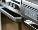 Nowoczesna kuchnia z piekarnikiem i zmywarką obok. Panel sterowania zmywarki z przyciskiem ON/OFF.