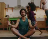 Man i lugn meditation i köket medan barn springer förbi. En lugn stund för 5 minute meditation mitt i vardagskaoset.