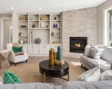 Un elegante mueble salones con chimenea de piedra, estanterías repletas de objetos decorativos y cómodos sofás.