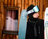 Młody narciarz w goglach i czapce trzyma narty. Wskazówki, jak przechowywać narty, aby służyły latami.