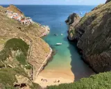 Idyllische Bucht mit weißem Sandstrand und türkisfarbenem Wasser auf den Berlengas Inseln. Kleine Boote ankern, Häuser schmiegen sich an die Felsen.
