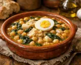 Garbanzos con bacalao, una receta tradicional servida en cazuela de barro, coronada con huevo duro.