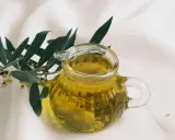 Aceite de oliva dorado en jarra de cristal, junto a rama de olivo. ¿Cuál es el aceite de oliva más suave?