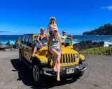 Fyra glada kvinnor på en gul jeep vid havet. Drömmen om att flytta till Hawaii känns nära!