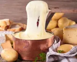 Fondue au fromage, un délice des spécialités culinaires auvergnates, avec du pain, des pommes de terre et du vin rouge.