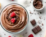 Mousse au chocolat sans jaune, onctueuse et aérienne, garnie de framboises fraîches et de copeaux de chocolat. Un délice léger et gourmand.
