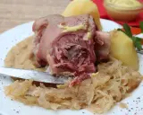 Un plat copieux de spécialités culinaires alsaciennes : jarret de porc, purée de pommes de terre et choucroute, garni de moutarde.