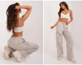 Modelka prezentuje luźne, beżowe spodnie cargo i biały top. Idealne pytanie: jakie buty do kulotów? Grube trapery świetnie uzupełniają ten look.