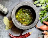 Frische Kräuter, Knoblauch, Schalotten und Chili – die chimichurri hauptzutaten werden im Mörser zubereitet.