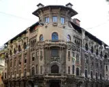Dettagli architettonici unici del **Palazzo Galimberti Milano**, con balconi ornati e sculture che emergono dalla facciata.