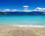 Idealne miejsce, gdzie lecieć w czerwcu: turkusowe morze, kamienista plaża i góry w tle. Idealny widok na wakacje.
