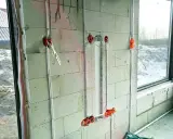 Instalacja elektryczna w ścianie z bloczków betonowych, etap prac wykończeniowych od stanu surowego zamkniętego. Widoczne puszki i przewody.
