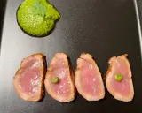 Cuatro lonchas de tataki de salmón con un toque de verde y una guarnición vibrante.