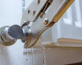 Pinzas sujetan una conexión de un radiador que gotea, con agua cayendo.