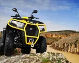 Un quad amarillo listo para conducir por terrenos escarpados junto a un río.