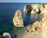 Felsformationen und türkisfarbenes Wasser an der Praia da Marinha, Algarve. Ein einsamer Felsen ragt aus dem Meer.