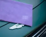 Fioletowa mikrofibra z logo Work Stuff na masce zielonego Aston Martina. Idealna do pielęgnacji auta.