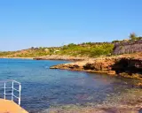 Scogliera rocciosa e mare cristallino a San Gregorio Salento, con una terrazza in primo piano.