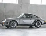 Grauer Porsche 911 G-Modell steht vor einer Betonwand.