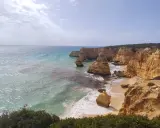 Acantilados dorados y mar turquesa en la ruta de los siete valles colgantes. Olas rompen en la arena de una playa escondida.