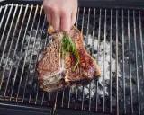 Ein saftiger florentiner steak wird mit Rosmarin auf dem Grill verfeinert.