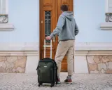 Mężczyzna z walizką Vanguard, która jest idealna do podróży. Vanguard co to za firma? To producent wysokiej jakości sprzętu fotograficznego i podróżniczego.