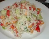 Une savoureuse salade de riz garnie de dés de tomates, de concombre et d'herbes fraîches, servie sur une assiette blanche.