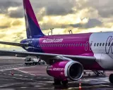 Samolot Wizz Air na płycie lotniska pod pochmurnym niebem.