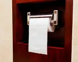 Uchwyt na papier toaletowy zamontowany jest na wygodnej wysokości, w ciemnej, drewnianej wnęce.