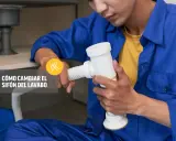 Un fontanero realiza la instalación del sifón del lavabo, sujetando la pieza blanca con ambas manos.