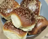 Pięć puszystych bułek do burgerów, posypanych sezamem, ułożonych na talerzu. Idealne na domowe burgery.