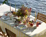 Enkel dukning vid vattnet med blommor och ljus.