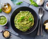 Pyszny obiad bez mięsa: spaghetti z pesto, świeżą bazylią, orzeszkami pinii i parmezanem.