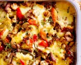 Herzhafter Gyros Auflauf mit geschmolzenem Käse, Pilzen und Paprika, garniert mit frischen Kräutern.