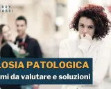 Una donna con espressione preoccupata osserva una coppia felice in lontananza, simbolo di gelosia tra donne.