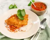 Krispig kyckling piccata serverad på ris med en smakrik tomatsås och färsk basilika. En härlig måltid!