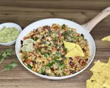 Pyszny kurczak po meksykańsku z fasolą, kukurydzą i serem, podany z guacamole i nachos.