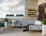 Przytulny balkon w bloku z szarą sofą, drewnianym stolikiem i kwitnącym bluszczem. Idealne miejsce na relaks po myciu balkonu w bloku.