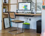 Bureau moderne avec iMac, chaise en rotin et étagères. Idéal pour savoir comment choisir un ordinateur de bureau adapté à votre espace de travail.
