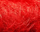 Un groviglio di fili rossi vibranti, una **fibra artificiale** che ricorda un nido intricato o capelli mossi dal vento.