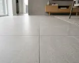 Suelo de salón moderno con azulejo rectificado de gran formato en tonos grises, creando un ambiente minimalista y elegante.