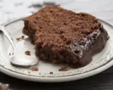 Pyszny murzynek z dżemem, polany czekoladą, czeka na talerzyku z łyżeczką.