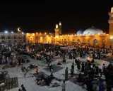Menschen versammeln sich nachts auf einem Platz vor einer Moschee, um die Qadr Nacht zu begehen.
