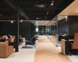 Un espace de travail innovant avec des canapés en cuir, des chaises modernes et des bureaux vitrés.