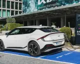 Un coche eléctrico blanco Kia EV6 cargando en un punto Kia Charge. Merece la pena un coche eléctrico por su tecnología y futuro.