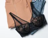 Un reggiseno di pizzo nero adagiato su jeans e felpa color cammello. Pensando a ogni quanto si cambia il reggiseno, questo è un capo che merita cura.