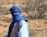 Ein Mann in traditioneller blauer Kleidung und Turban blickt aus der Wüste. Sind Marokkaner Araber? Ja, viele Marokkaner sind Araber.
